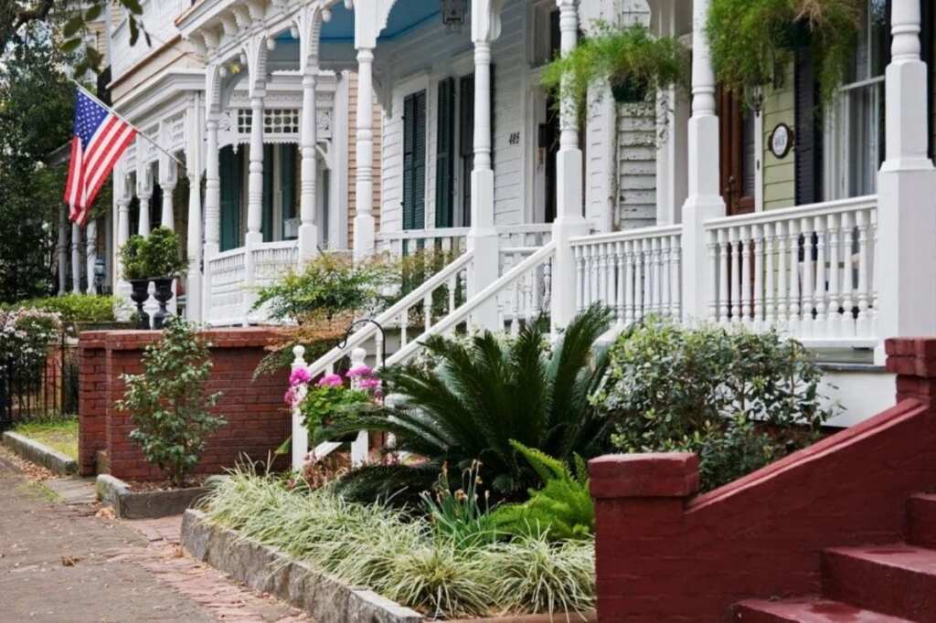Casas coloniais em Savannah EUA com varandas decoradas e bandeira americana em bairro histórico