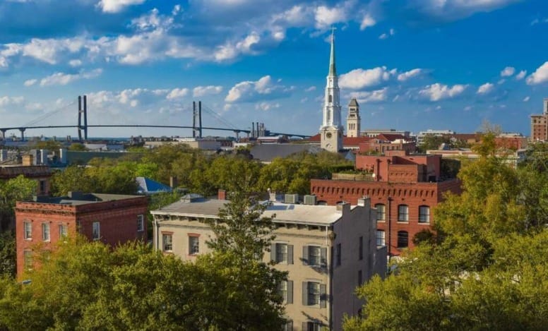 Vista panorâmica de Savannah EUA com prédios históricos, árvores e a ponte Talmadge Memorial ao fundo