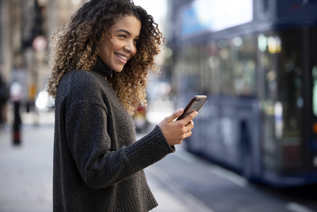 young woman using her smartphone city min
